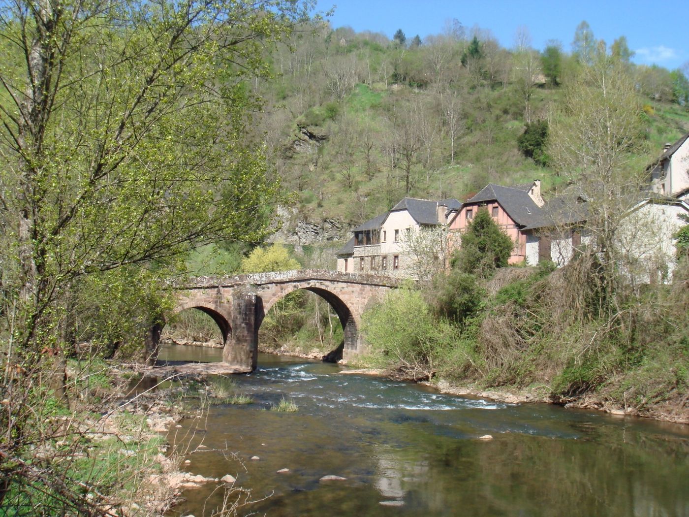 Pont de pierre médiéval enjambant une rivière dans un village de l’Aveyron
